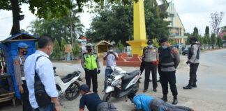 Dua karyawan PLN saat disanksi petugas karena terjaring Operasi Yustisi di Tugu Kuning, Kampung Tri Tunggal Jaya, Kecamatan Banjar Agung