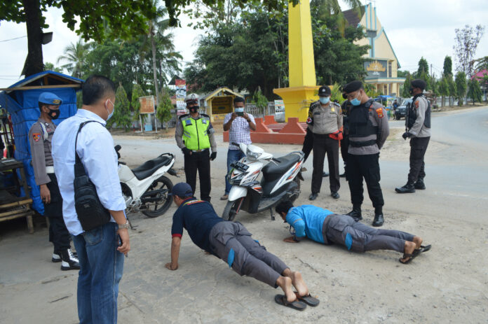 Dua karyawan PLN saat disanksi petugas karena terjaring Operasi Yustisi di Tugu Kuning, Kampung Tri Tunggal Jaya, Kecamatan Banjar Agung